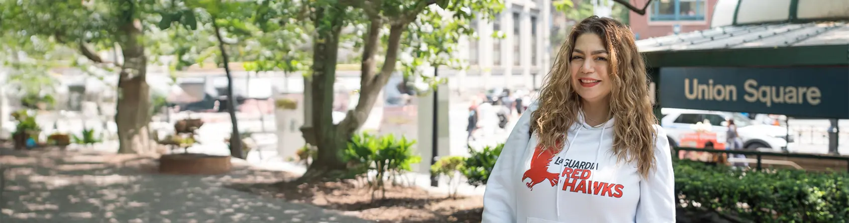 Student outside Union Square posing for a picture while wearing LaGuardia Merchandise
